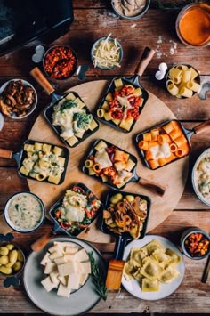 a wooden table topped with lots of different types of food and bowls filled with sauces