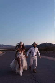 a man and woman walking down the road in their wedding attire, dressed in white