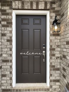 a welcome sign is on the front door of a brick building with a lamp post