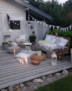 a deck with chairs, tables and candles in the middle of it is lit up by string lights