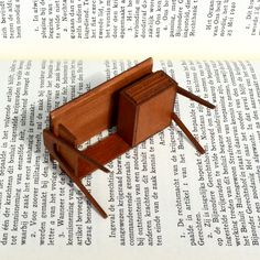 a wooden toy mouse trap sitting on top of an open book with pages in the background