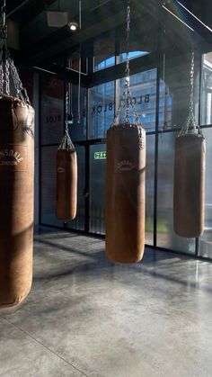 three brown boxing bags hanging from chains