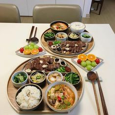 two plates filled with different types of food on top of a white tablecloth covered dining room table