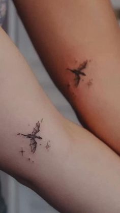 two people with tattoos on their legs, one has a small bird and the other has stars