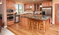 a kitchen with wooden cabinets and stainless steel appliances, along with an island in the middle