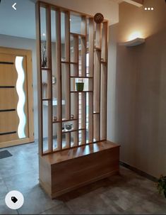 a wooden shelf sitting in the middle of a living room next to a planter