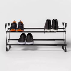 two pairs of shoes are sitting on a shoe rack that holds three pairs of sneakers