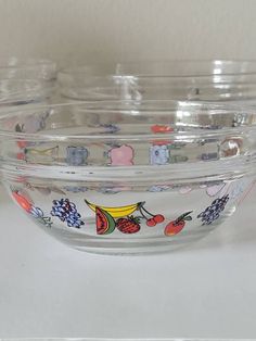 three glass bowls with fruit designs on them