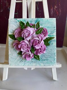 a painting with purple flowers on it sitting on a easel