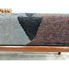 an upholstered bench with several different colored pillows on it's back and sides