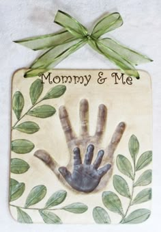 a ceramic plaque with a hand and green leaves on it that says mommy & me