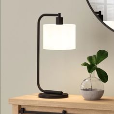 a lamp that is on top of a table next to a potted plant and mirror