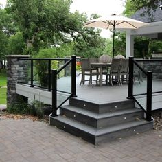 a deck with an umbrella over it next to a table and chairs on the other side