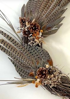 two feathers with pine cones and dried flowers