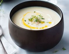 a black bowl filled with soup next to a spoon and napkin on top of a table