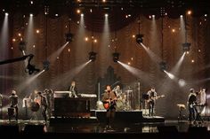 a group of people that are standing on a stage with lights in front of them