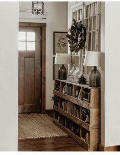 an entry way with a book shelf, lamp and pictures on the wall above it