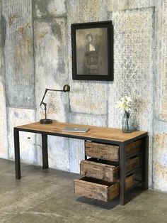 a desk with drawers in front of a stone wall and framed photograph on the wall