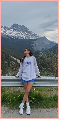 a woman is sitting on a bench looking up at the mountains and snow capped peaks