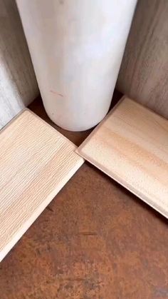 two pieces of wood sitting on top of a wooden floor next to a white vase