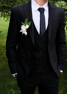 a man in a black suit and white flower boutonniere