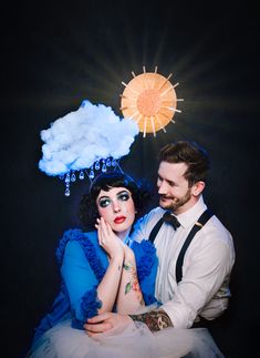 a man and woman are posing for a photo in front of the sun with clouds above them