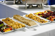 several trays of food sitting on top of a white table covered in paper towels