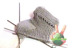 a pair of knitted mittens sitting next to knitting needles