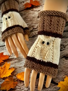 two hands wearing knitted mittens and gloves on top of a wooden table with autumn leaves