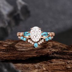 a diamond and turquoise stone ring sitting on top of a tree branch