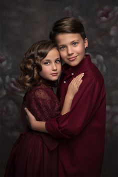 two children hugging each other in front of a dark background