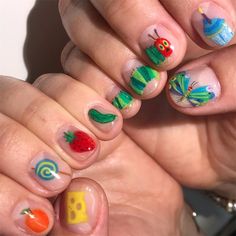 a woman's hands with colorful nail art on them and fruit, vegetables and cheeses painted on their nails