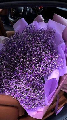 a bunch of purple flowers sitting in the back seat of a car with its door open