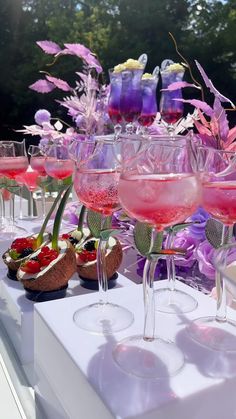 a table topped with lots of glasses filled with different types of drinks and desserts