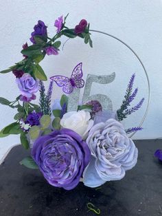 purple and white flowers are arranged in front of the number five sign on a table