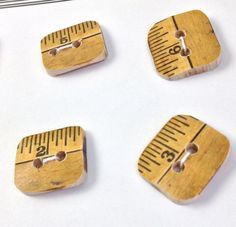 four wooden buttons with measuring tape on them