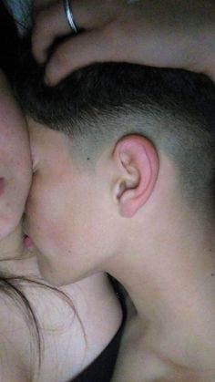 two people laying next to each other with their eyes closed and one person kissing the other