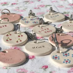 six ceramic key chains with different designs on them sitting on a flowered tablecloth