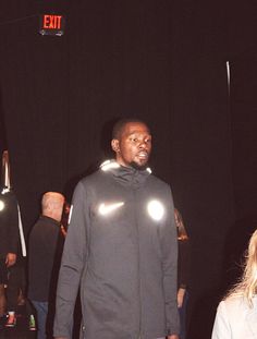 a man standing next to a woman in front of a black curtain with lights on it