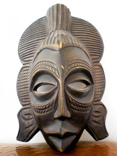 an african mask is sitting on top of a wooden table