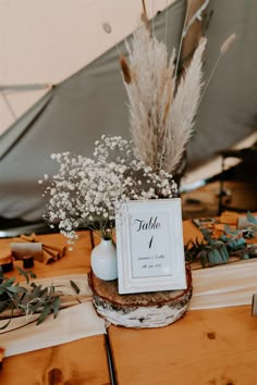 a table topped with a vase filled with flowers and a sign that says table 1