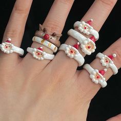 a woman's hand with five rings decorated like santa claus and mrs clauses