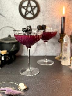 two glasses filled with liquid sitting on top of a table next to candles and other items