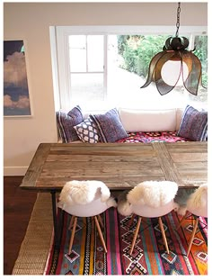 the table is made out of wood and has four chairs on it, with different colored rugs