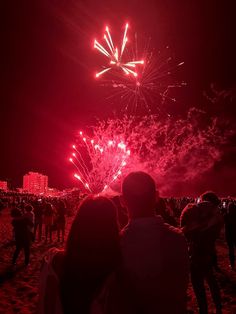 people watching fireworks on the beach at night