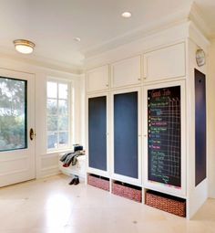 a kitchen with white cabinets and chalkboard on the wall in front of it's windows