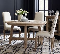 a dining room table with white chairs and an area rug