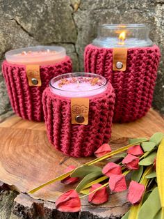 three red knitted candles sitting on top of a tree stump