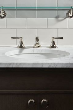 a bathroom sink with two faucets on the side and a marble counter top