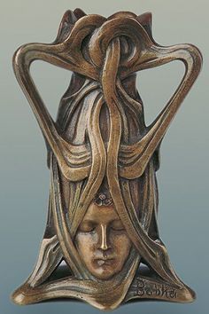 a bronze statue with an intricate head on it's face and hands in the shape of a woman's head